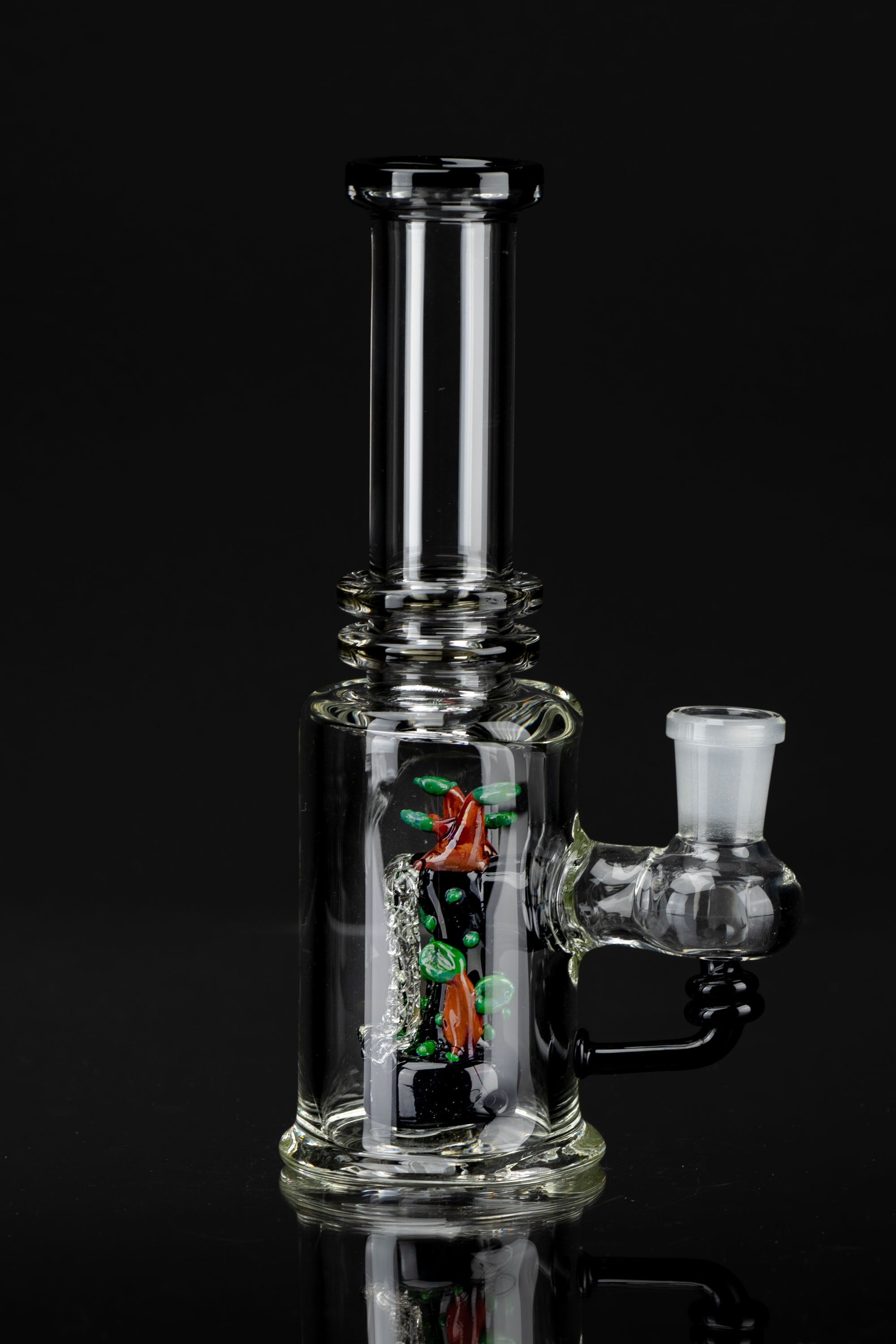Glass water pipe (bong) with colorful internal percolator, studio shot on reflective surface.