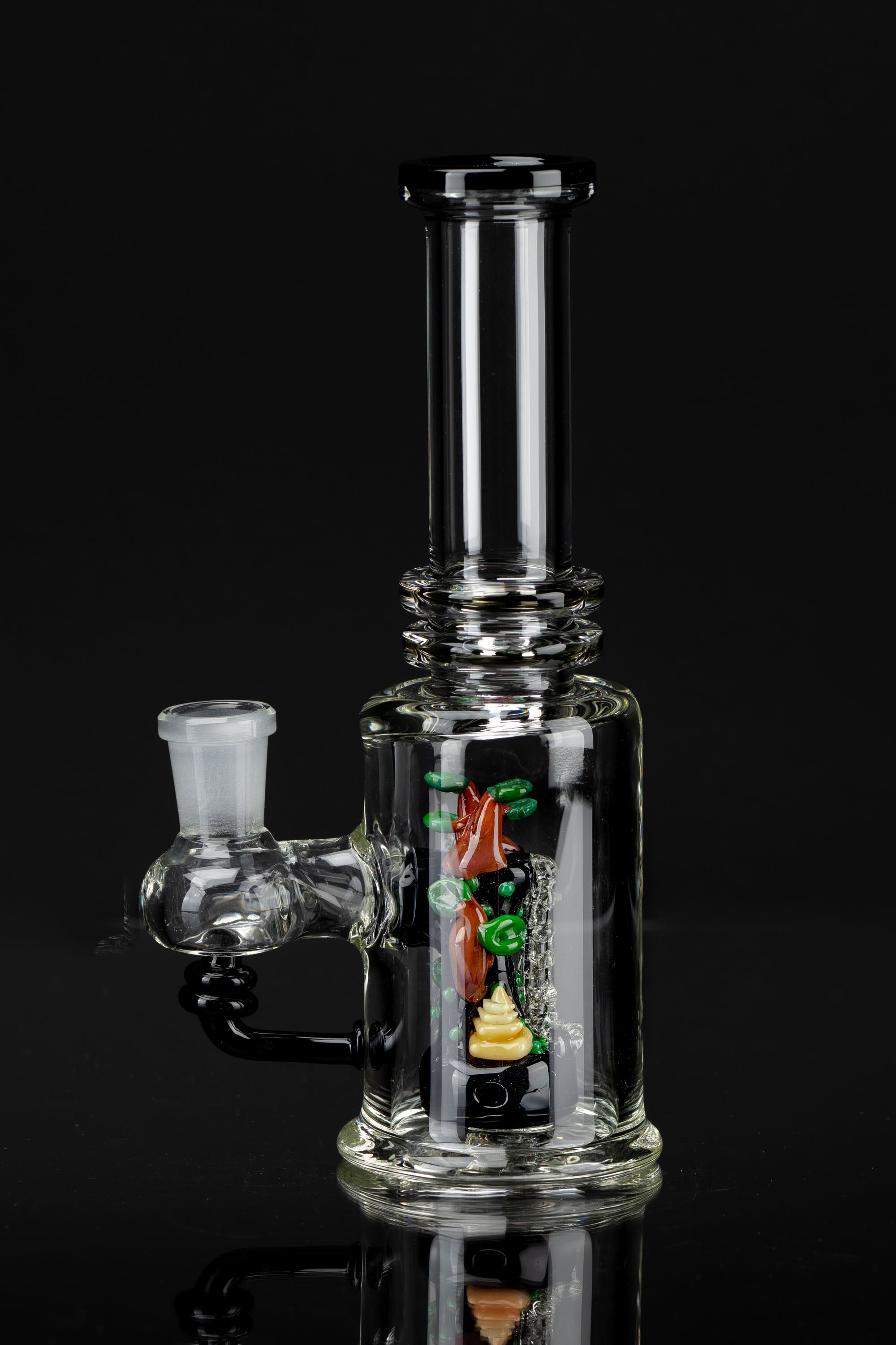 Clear glass water pipe (bong) with colorful glass sculpting inside, reflecting on a dark surface.