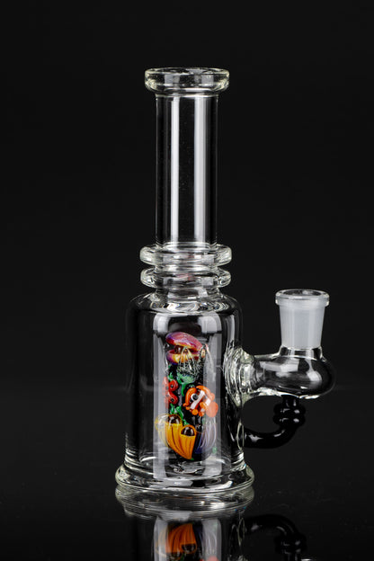 Clear glass bubbler with colorful sculpted glass inside, reflecting on a dark surface.