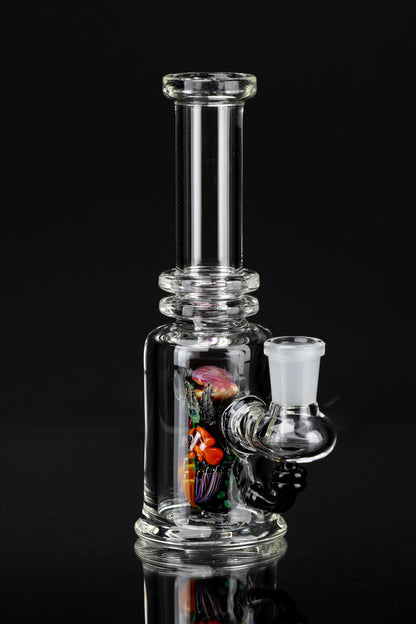 Clear glass bubbler water pipe with colorful glass inserts, studio shot on black.