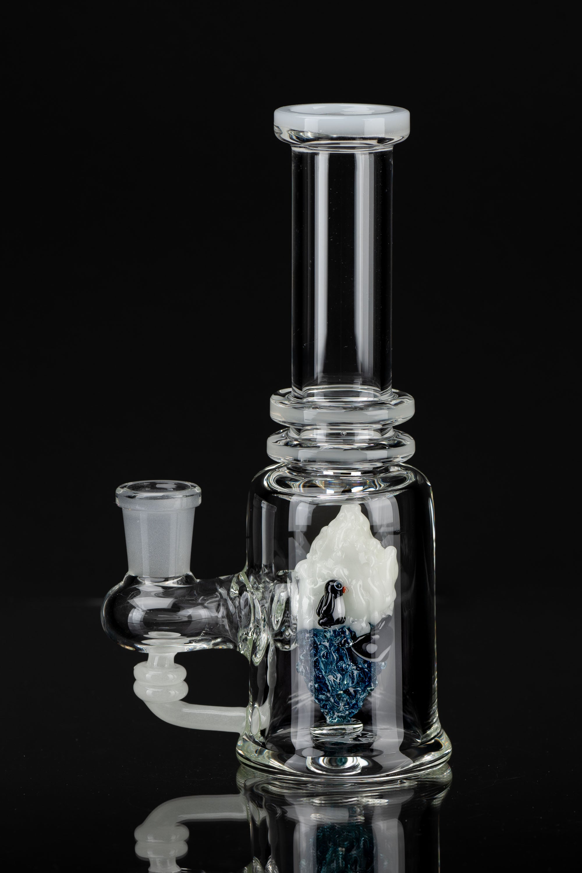Clear glass water pipe (bubbler) with blue and white accents, studio shot on black.