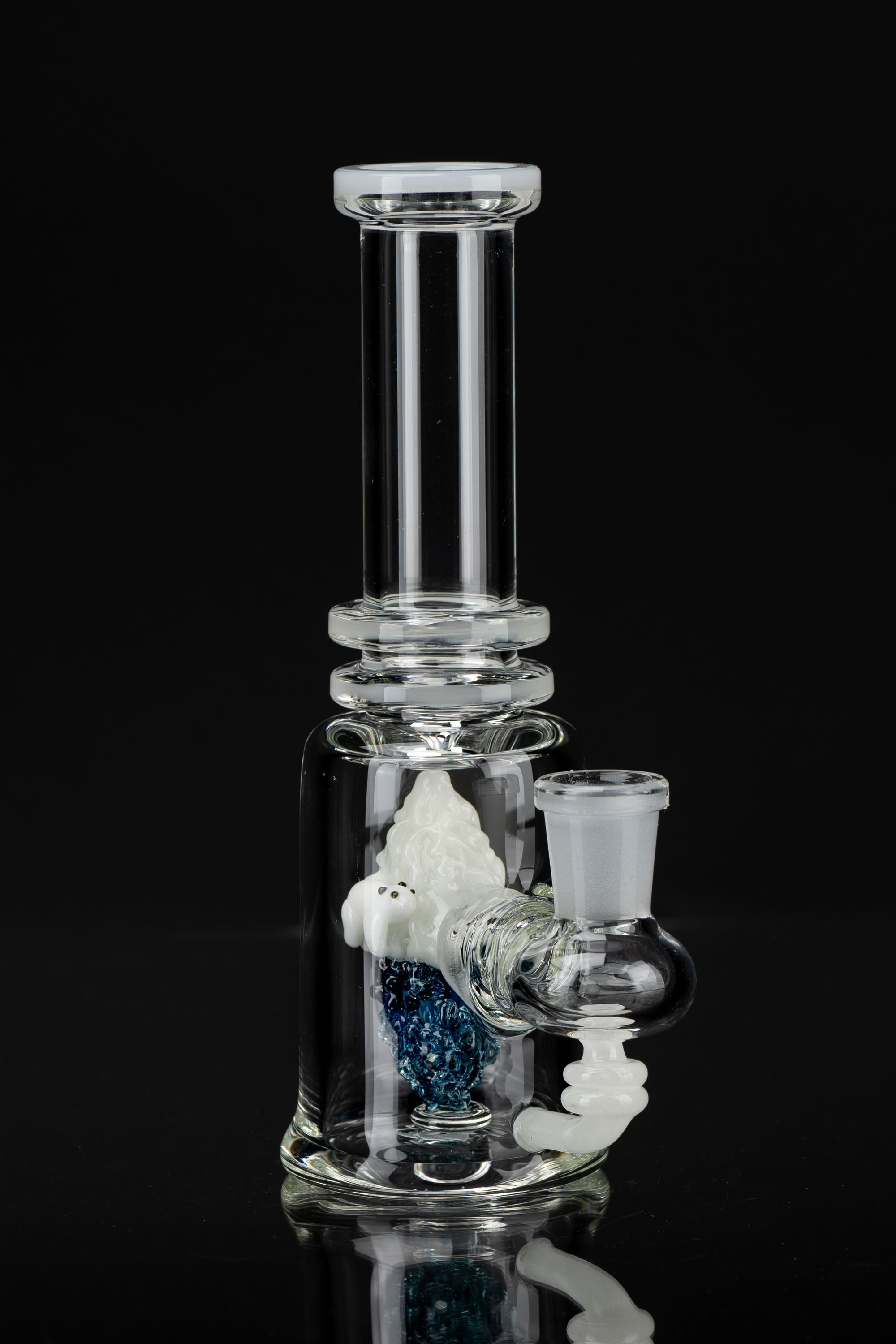 Clear glass water pipe (bong) with blue and white patterned glass accents, studio shot on black background.