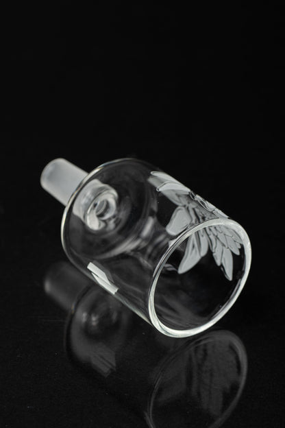 Clear glass cannabis bowl with floral etching, isolated on black.