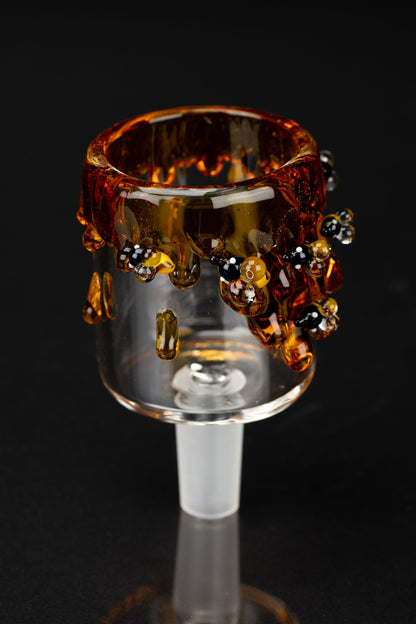 Close-up front view of the Empire Glassworks Bee PuffCo Proxy Attachment showing amber drips and tiny black-and-yellow bead details against a dark background.