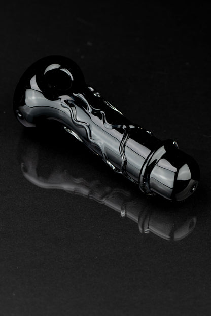 Black glass cannabis pipe with swirling design, reflecting on a dark surface.