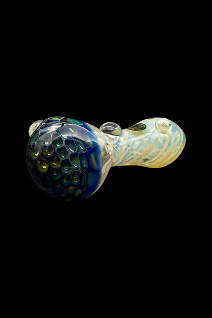 Hand-blown glass pipe with iridescent green and cream swirls against a black background.