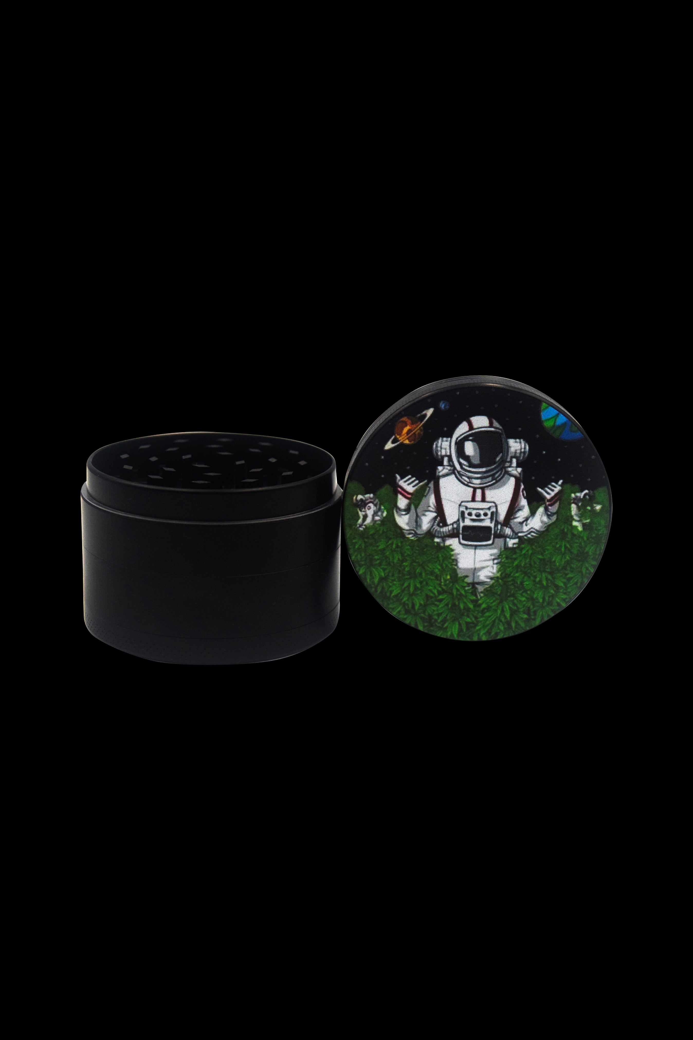 Black cannabis grinder with a lid depicting an astronaut in a field of green leaves.