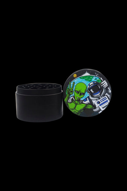 Black grinder with a colorful lid depicting an alien astronaut making a peace sign.