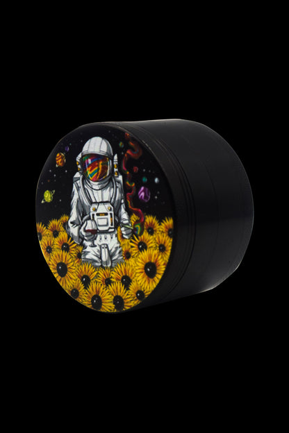 Black grinder with a colorful illustration of an astronaut sitting amongst sunflowers and cosmic elements.