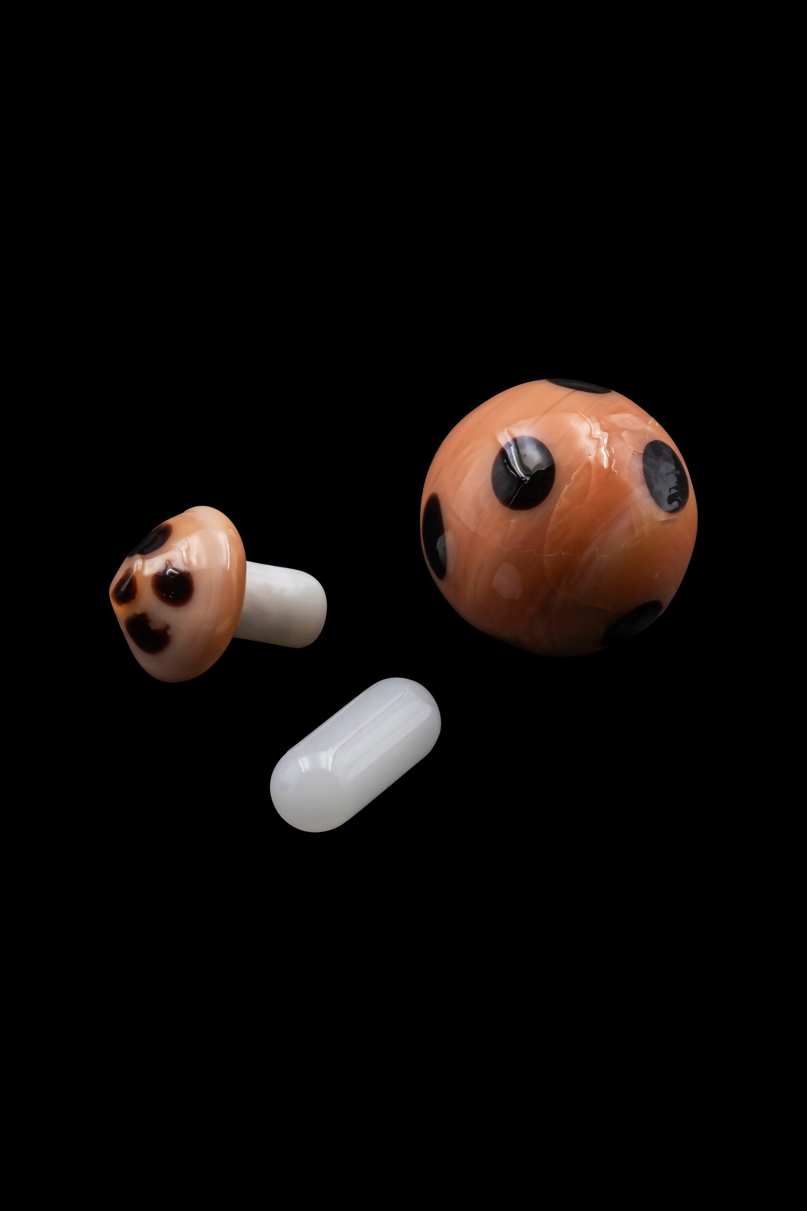 Floating glass mushroom and cylindrical cannabis accessories on a black background.