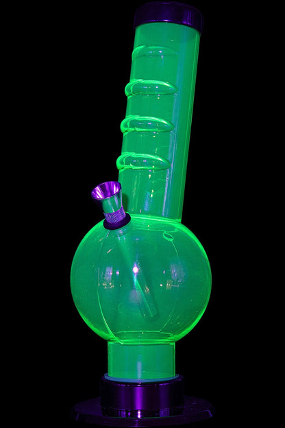 Glowing green glass water pipe (bong) with purple accents on a black background.