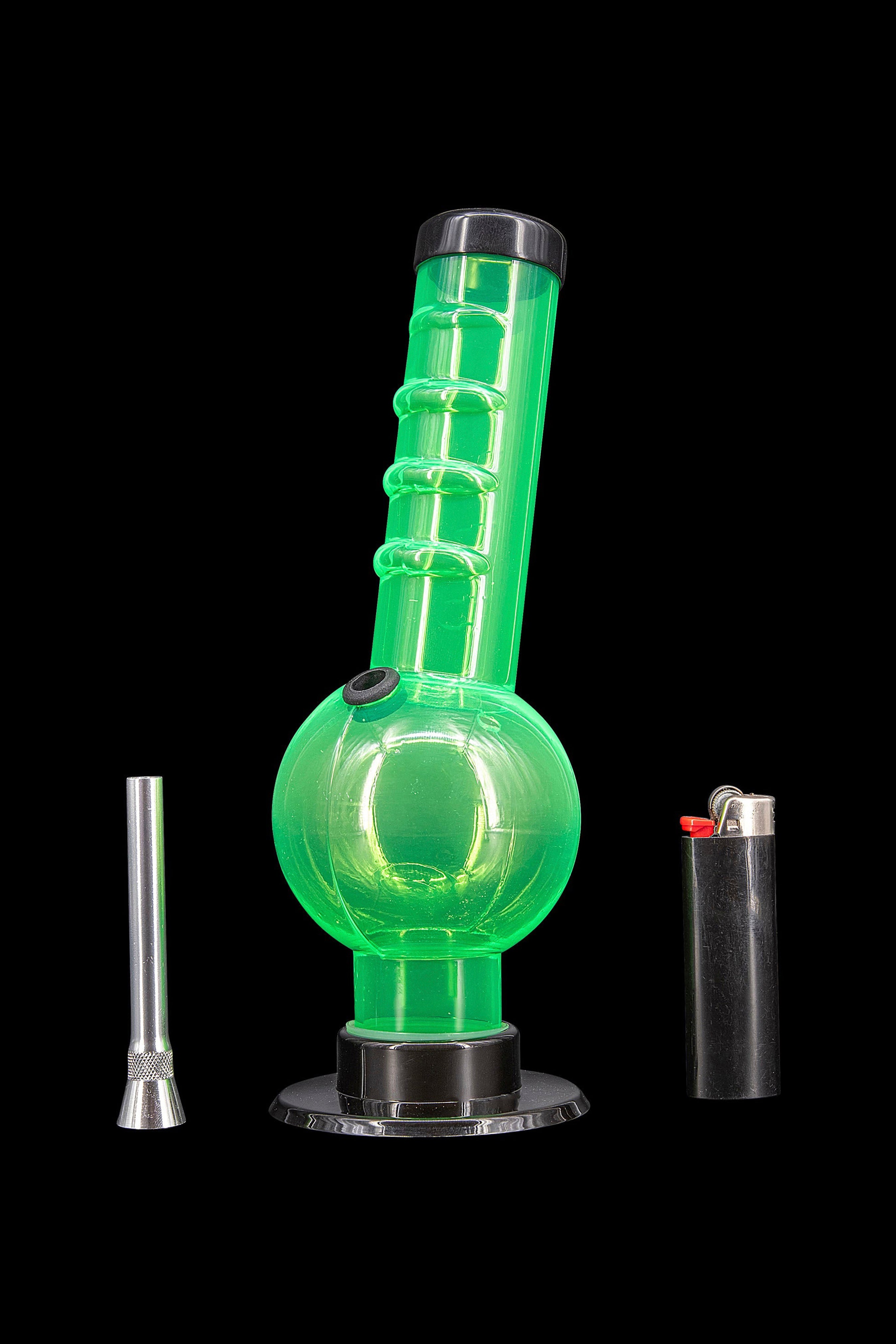 Green glass water pipe (bong) with a metal downstem and lighter on a black background.