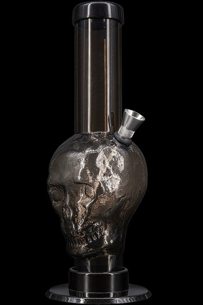 Black glass skull-shaped water pipe (bong) isolated on a black background.
