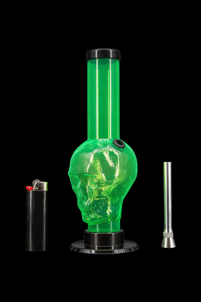 Green glass skull-shaped water pipe with lighter and metal downstem on black background.