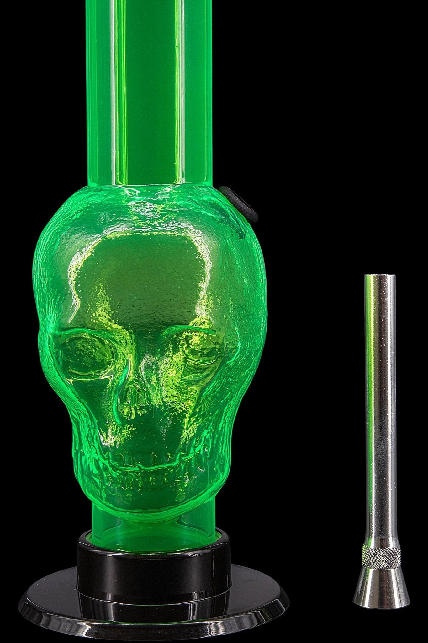 Green glass water pipe shaped like a skull with a metal downstem, isolated on black.