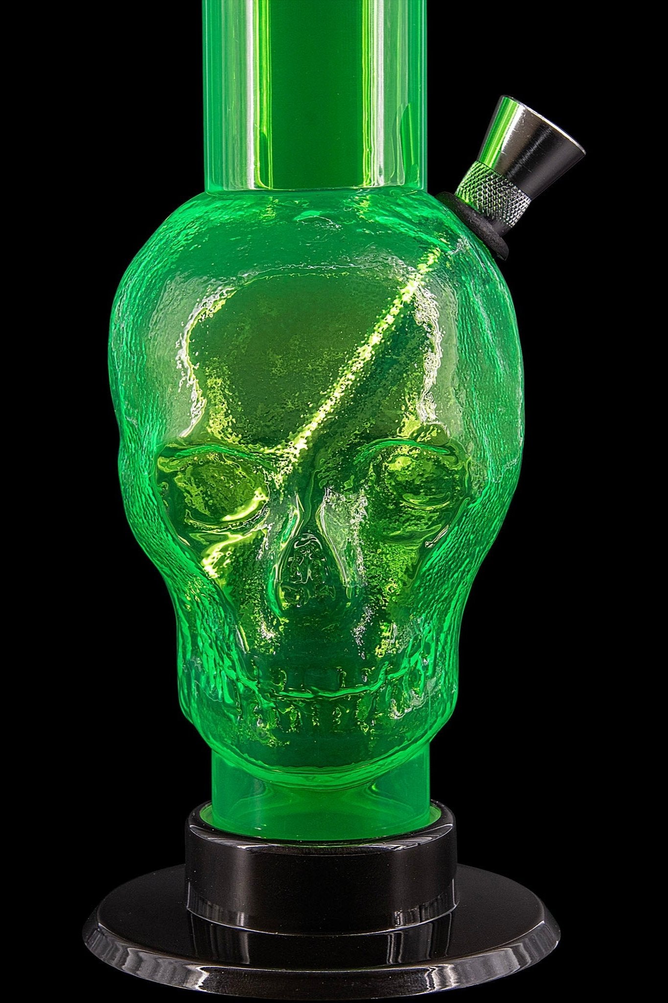 Green glass skull-shaped water pipe against a black background.