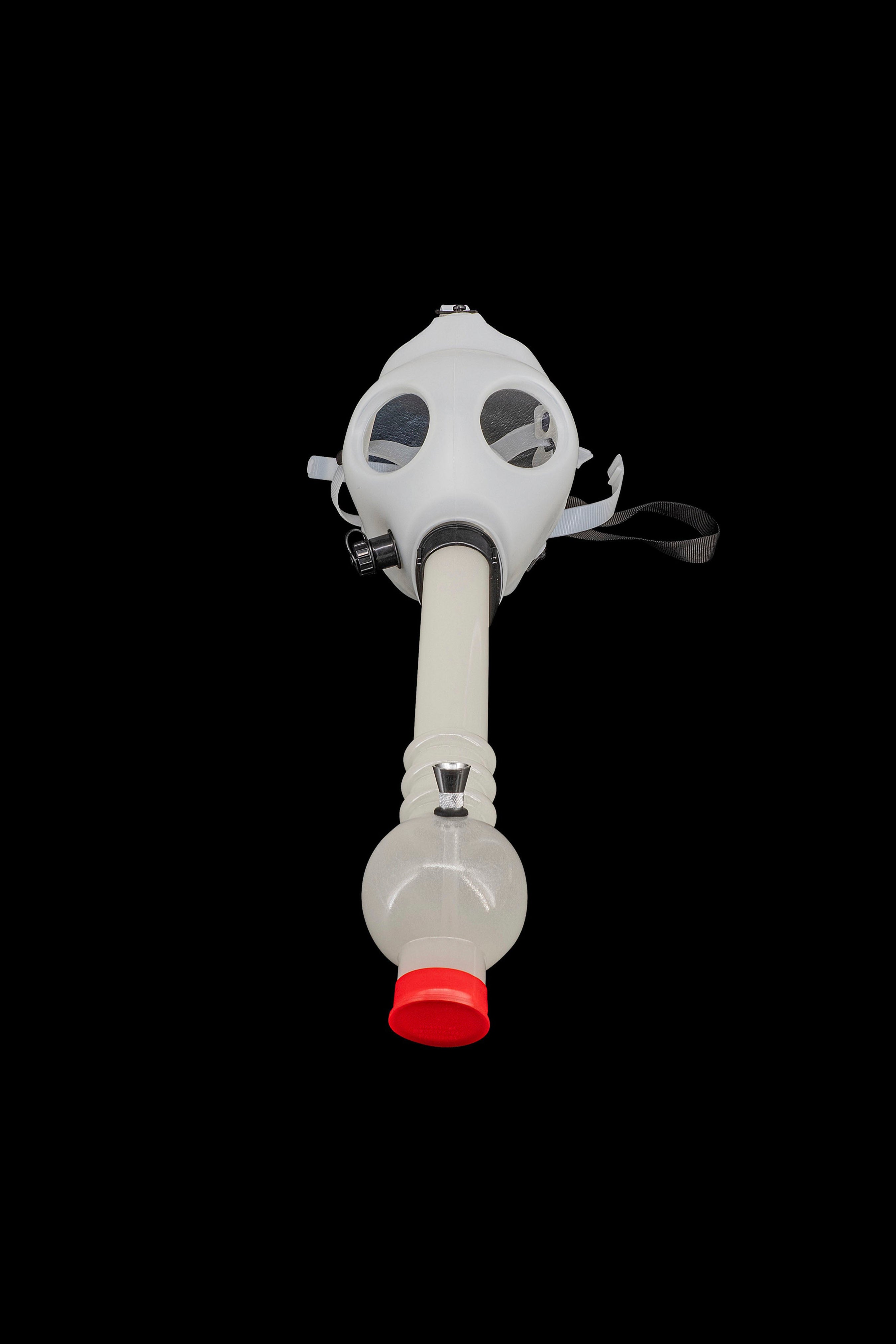 Gas mask bong with a red mouthpiece, isolated on a black background.