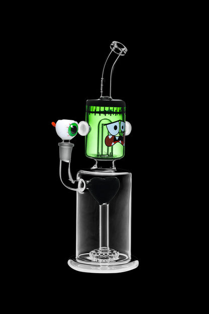 Green glass water pipe shaped like a monster with cartoon eyes, featuring a percolator base and clear mouthpiece.