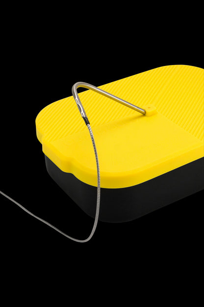 Yellow and black silicone container with a dab tool resting on top.