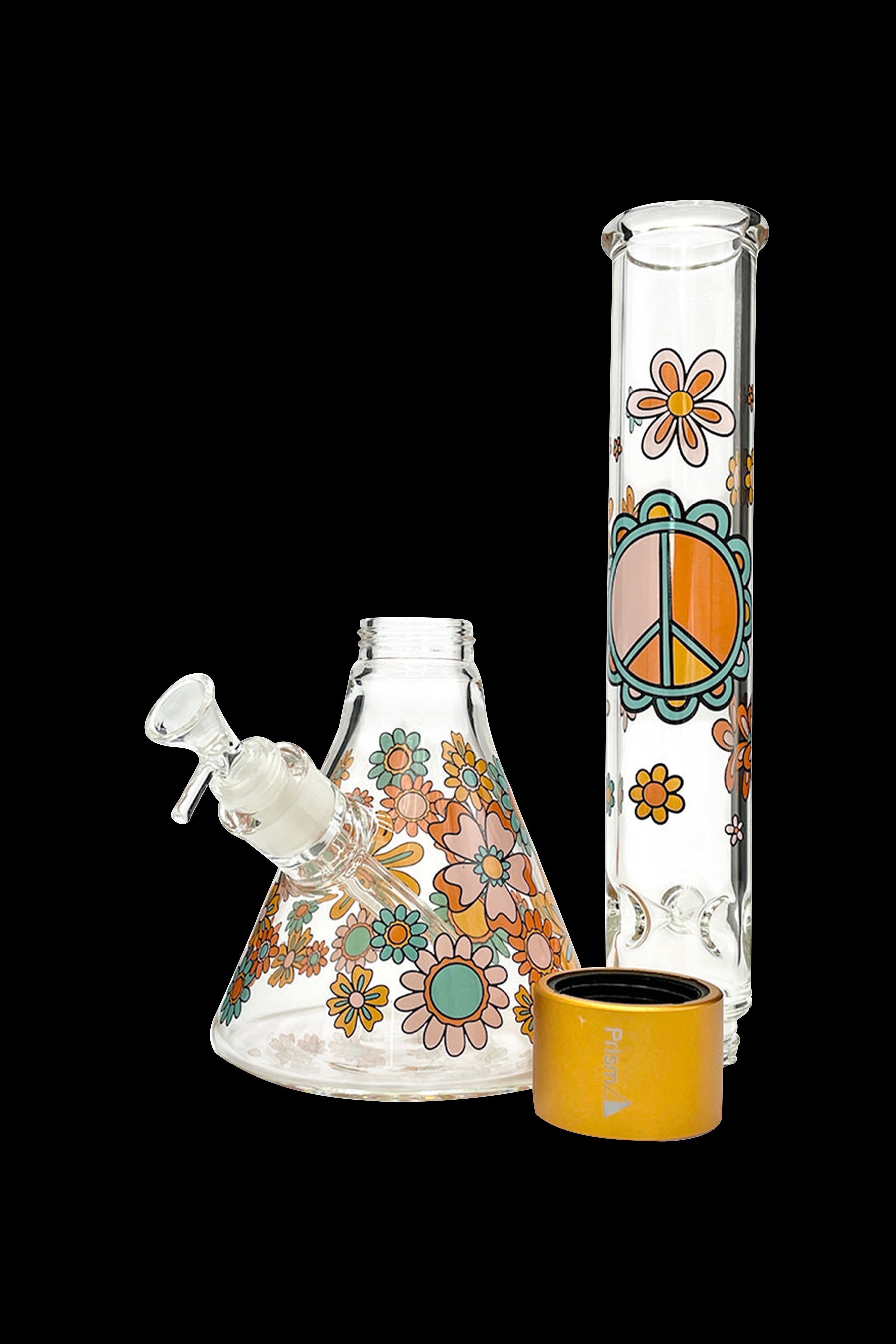 Glass bongs with colorful floral and peace sign designs, alongside a matching yellow-toned cap, isolated on a black background.