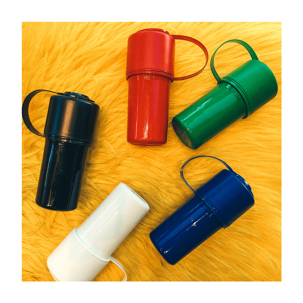 Glossy, colorful cannabis containers in red, green, blue, black, and white arranged on a textured yellow surface.