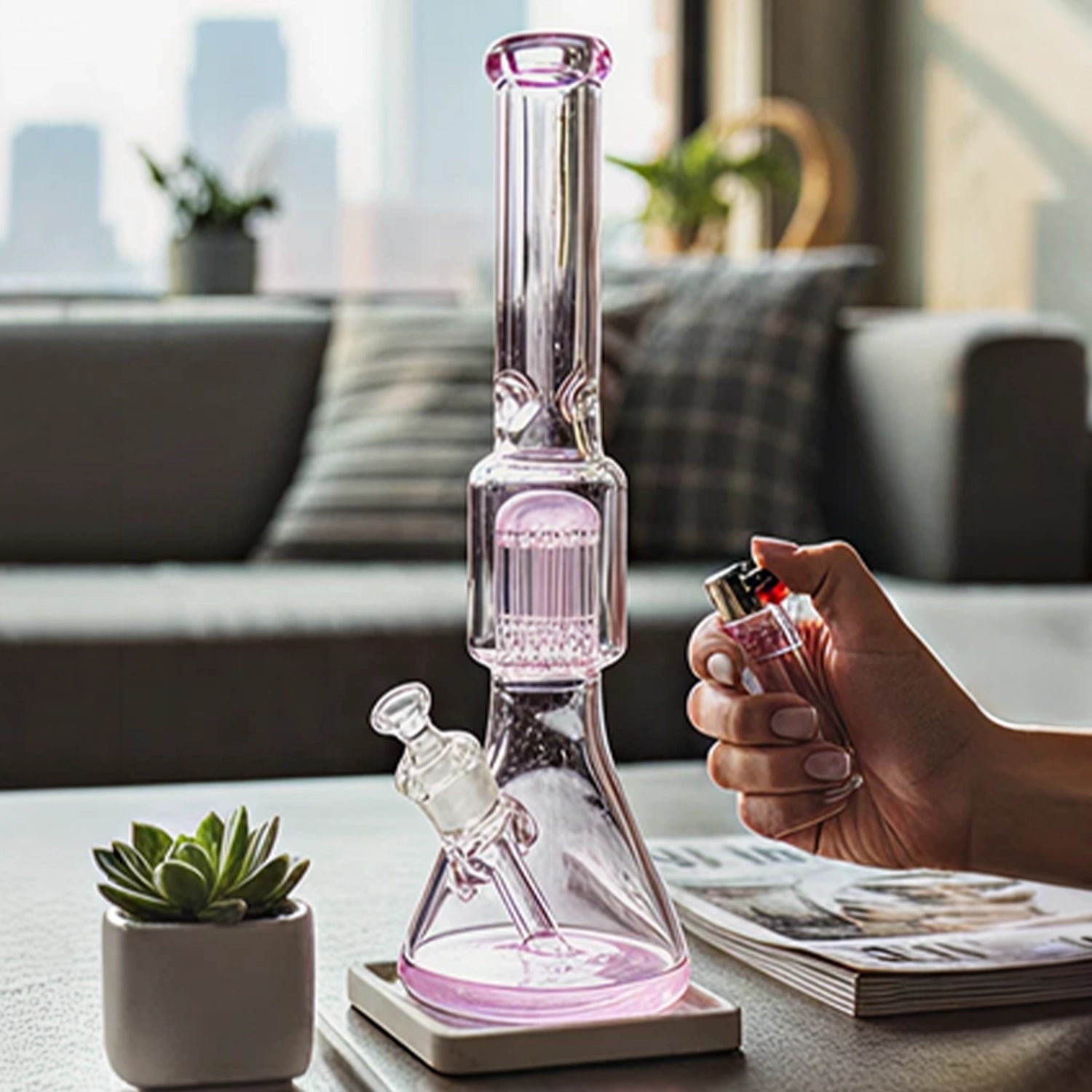 Center-framed Smoke Cartel 9mm Beaker w/ Tree Perc Bong in pale pink glass on a coffee table with a hand holding a lighter.