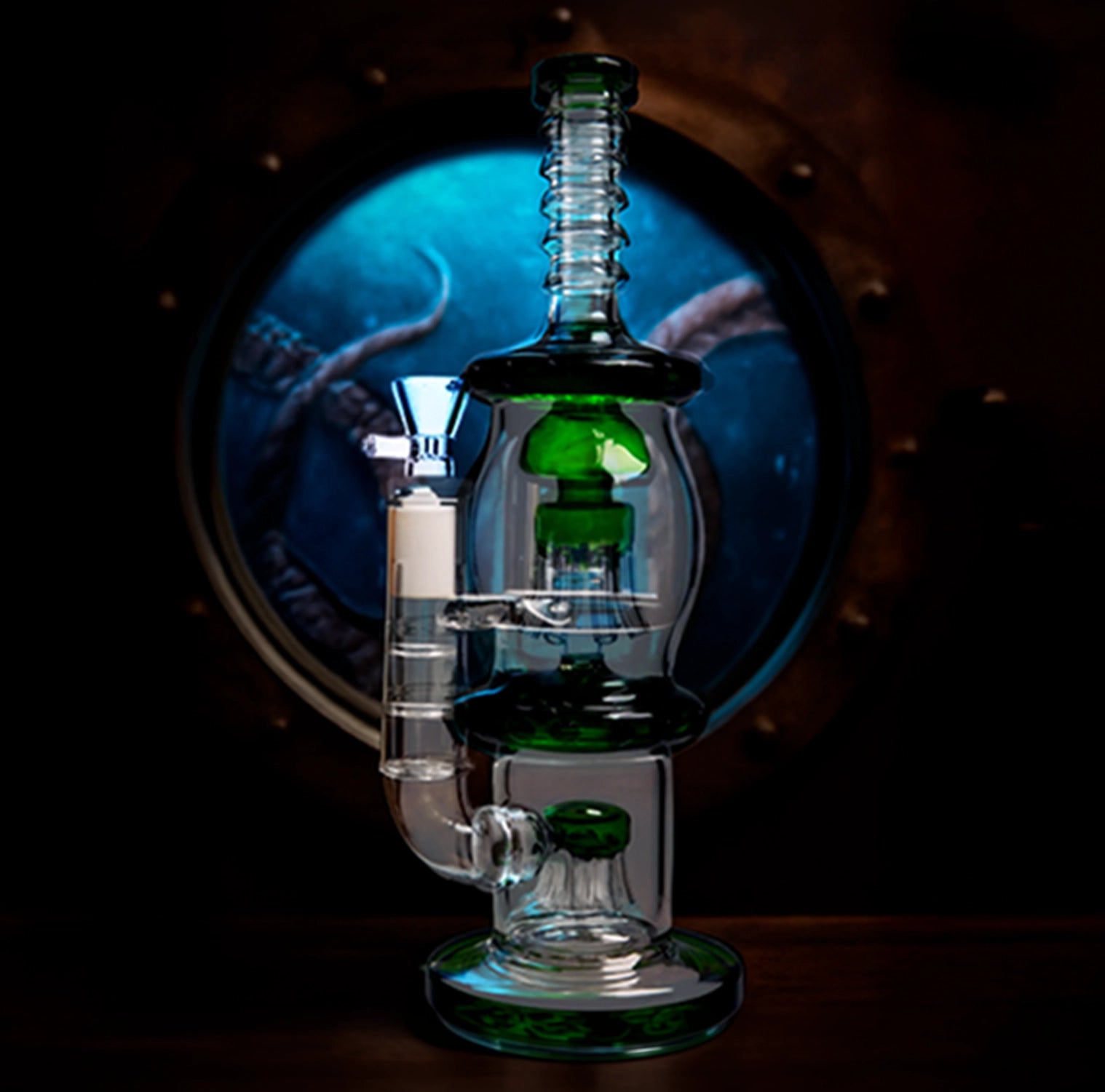 Center-front view of the Smoke Cartel Straight Tube w/ Dual Octopus Perc - 13.5 in. showing clear glass with green accents against a dark porthole-like blue background.