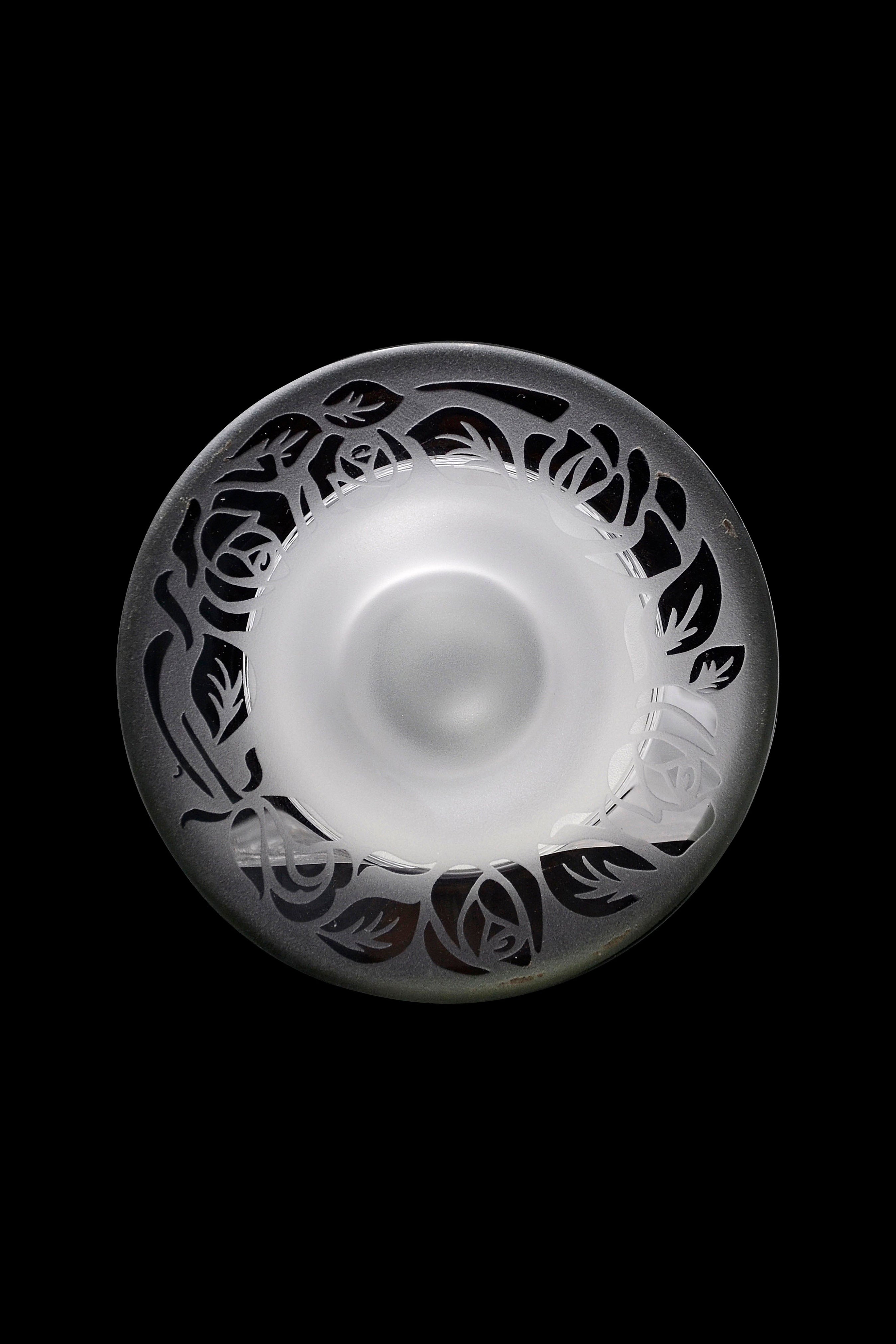 Ornate glass pipe with floral carvings, isolated on a black background.