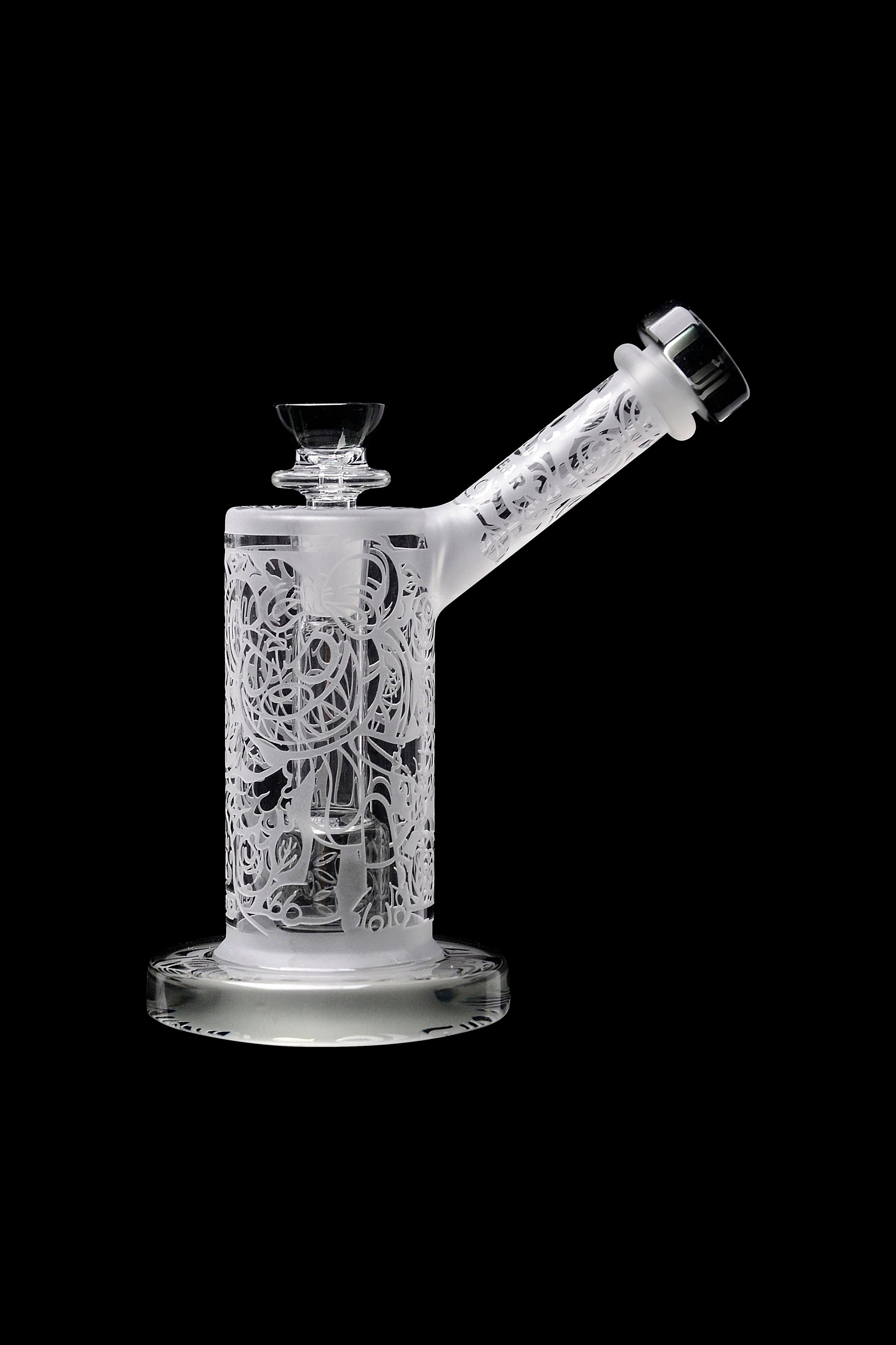 Frosted glass water pipe with intricate laser-cut designs, isolated on black.