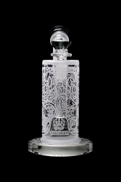 Clear glass cannabis oil concentrate container with intricate floral carving and “Calibear” branding.
