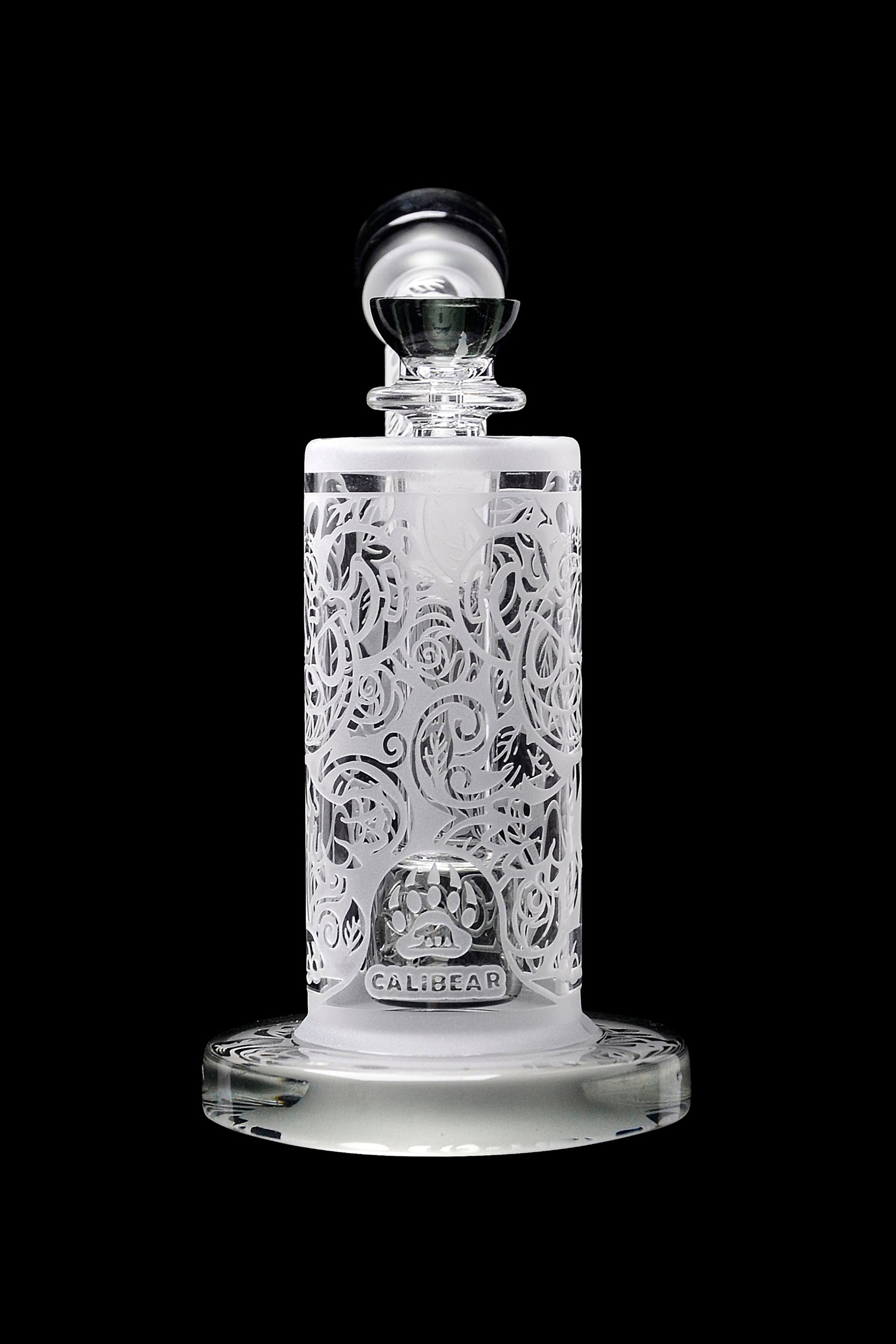 Intricate glass cannabis oil rig with ornate floral carvings and a branded base.