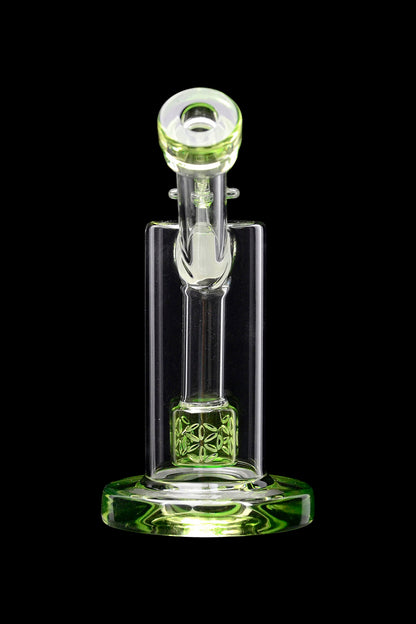 Green glass rig with intricate floral design, isolated on black.