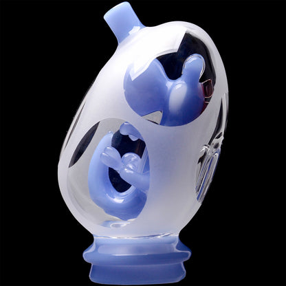 Close-up angled view of the Glassic Frosted Dino Egg Puffco Peak Glass Attachment showing frosted outer glass with glossy pale blue inner sculpted details against a black background