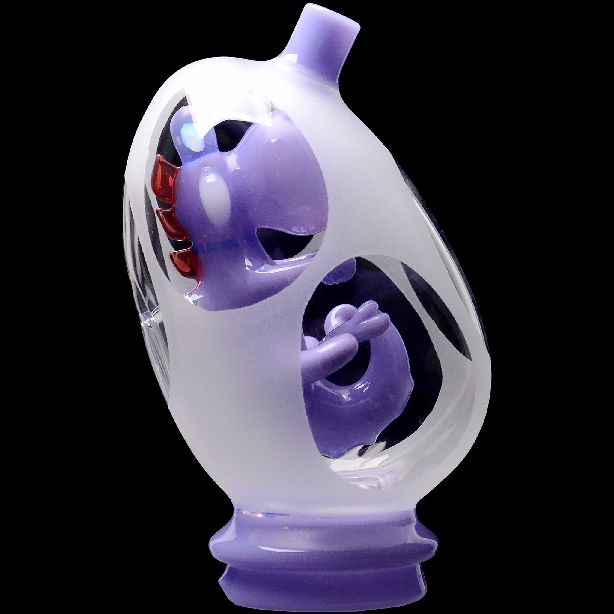Close-up three-quarter view of the Glassic Frosted Dino Egg Puffco Peak Glass Attachment showing frosted outer glass with purple inner sculpted dino details against a black background