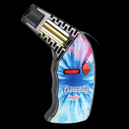 Angled close-up of the Grateful Dead Thrust Torch showing its open top, gold fuel chamber and kaleidoscope-style blue and pink tie-dye body against a black background.