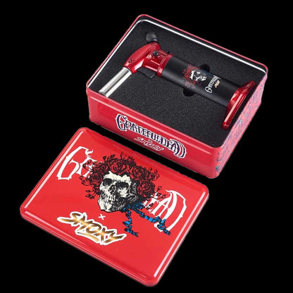 Angled top view of the Grateful Dead Vulcan Torch nestled in black foam inside a red tin decorated with a skull and roses.