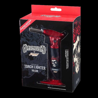 Angled front view of the Grateful Dead Vulcan Torch in its black and red windowed box, showing the red torch head and skull artwork.