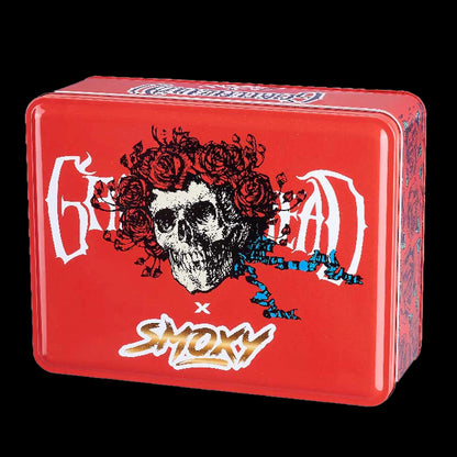 Angled close-up of the red Grateful Dead Vulcan Torch tin showing a skull crowned with roses and blue ribbon graphics against a black background