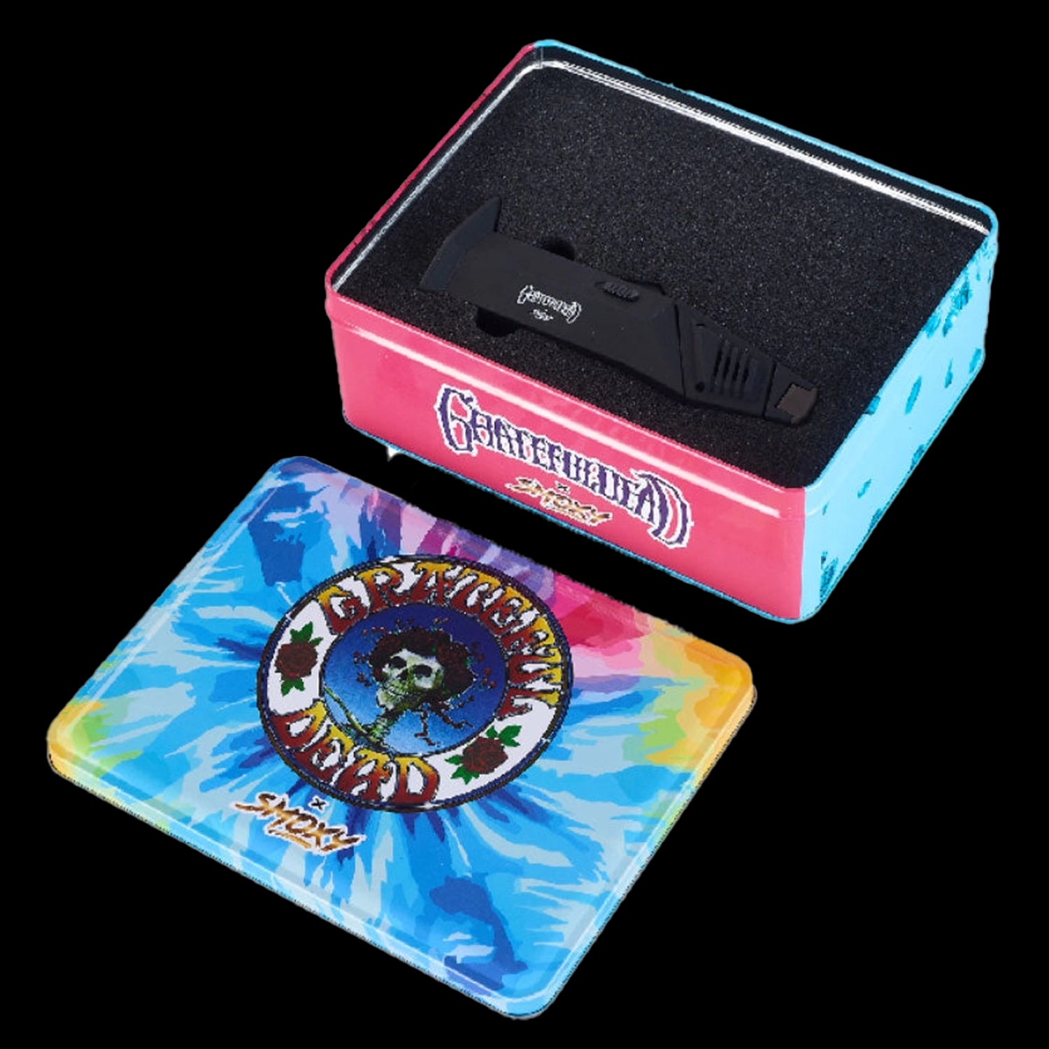 Angled top-down view of the Grateful Dead Flex Torch resting in black foam inside a pink and blue Grateful Dead tin beside a tie-dye lid.