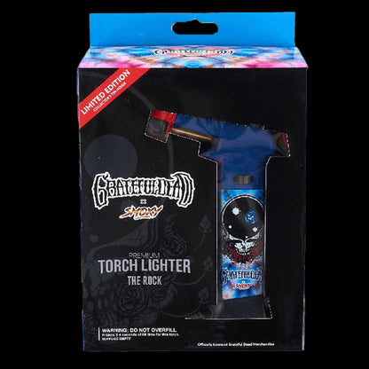 Front-facing boxed view of the Grateful Dead The Rock Torch with its blue skull-decorated lighter visible through a window.