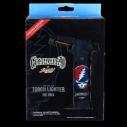 Front view of the boxed Grateful Dead The Rock Torch showing the torch lighter through a die-cut window and its skull/bolt graphics.