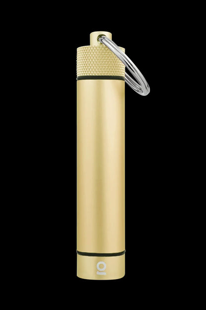 Gold-colored, cylindrical cannabis oil vape cartridge with a keyring attached, isolated on a black background.