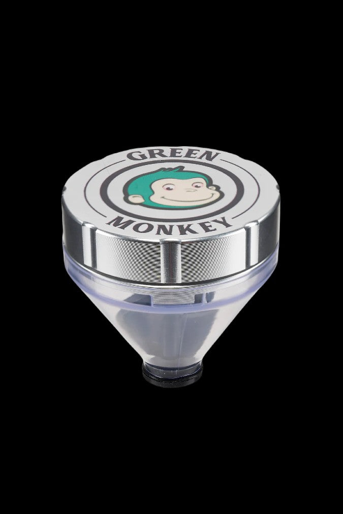 Top-down view of the Green Monkey Patas Grinder showing its silver lid with a green-haired monkey logo and clear funnel base.