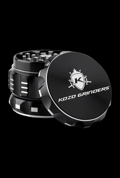 A close-up, angled view of the Kozo Grinder 2| showcasing its metallic, multi-tiered design against a dark backdrop.