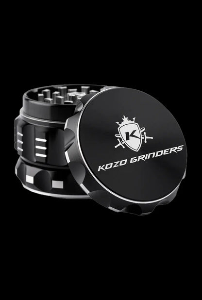A close-up, angled view of the Kozo Grinder 2| featuring a metallic, multi-tiered design against a dark background.