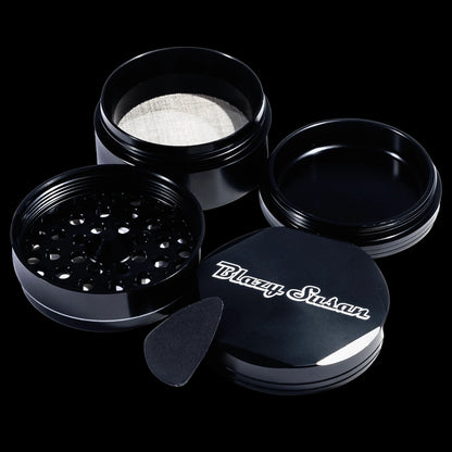 Angled top-down view of the black Blazy Susan 4-pc 3 Chamber Grinder showing its open threaded compartments, mesh screen, and lid.