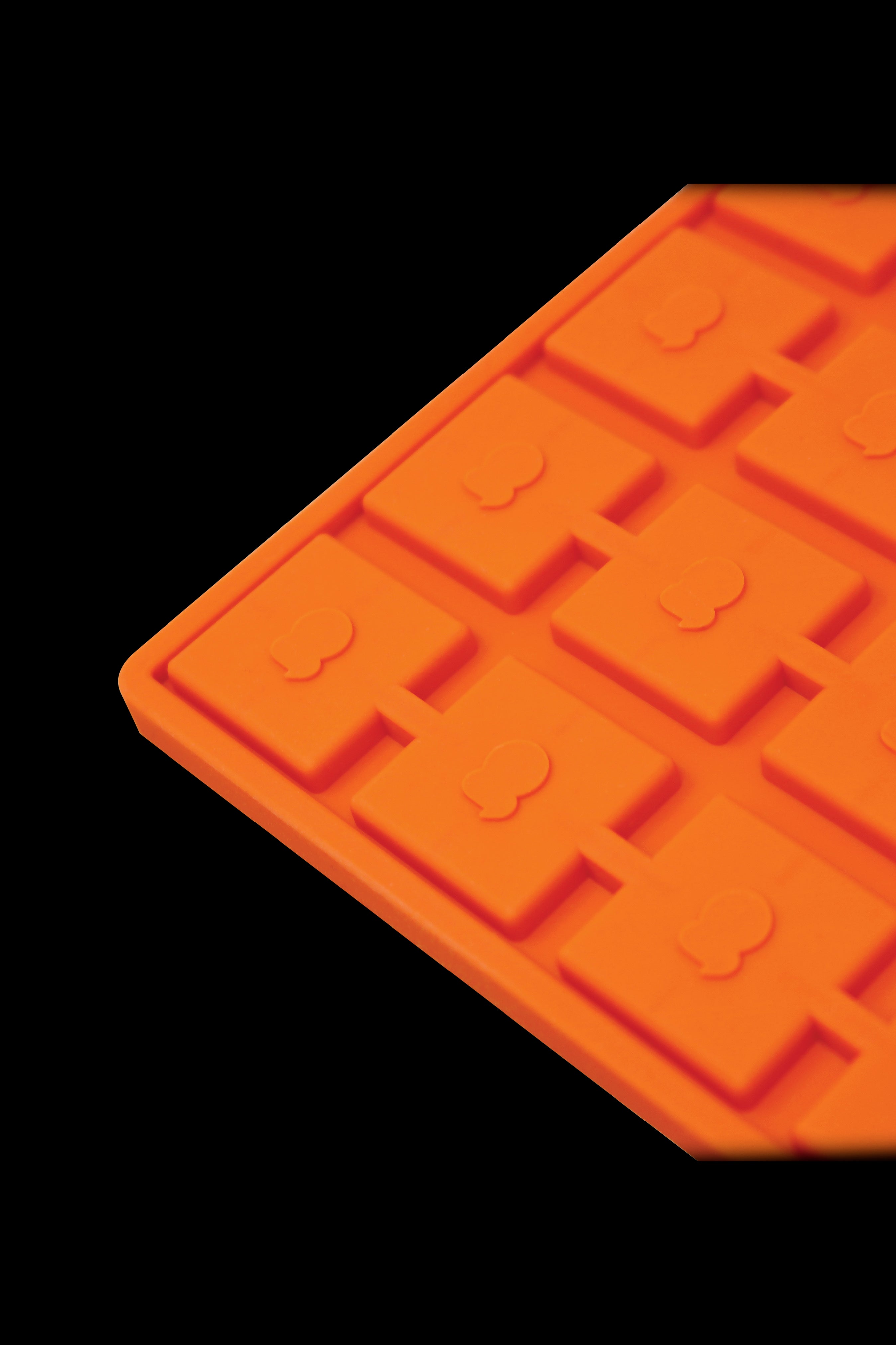 Orange silicone ice cube tray with cannabis leaf-shaped molds.