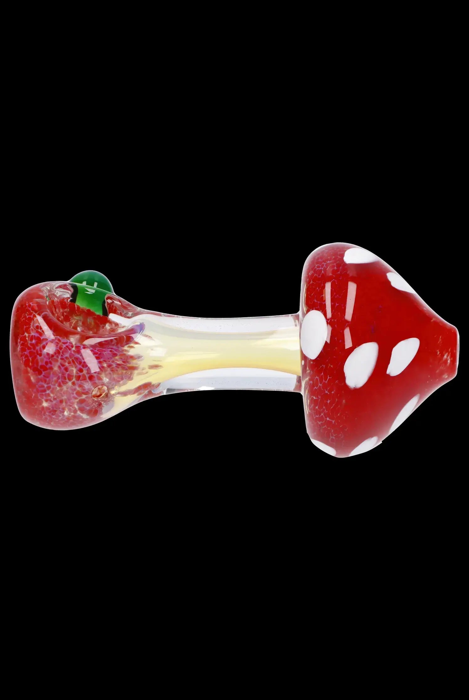 Red glass mushroom pipe with white spots and a green leaf detail, isolated on a black background.