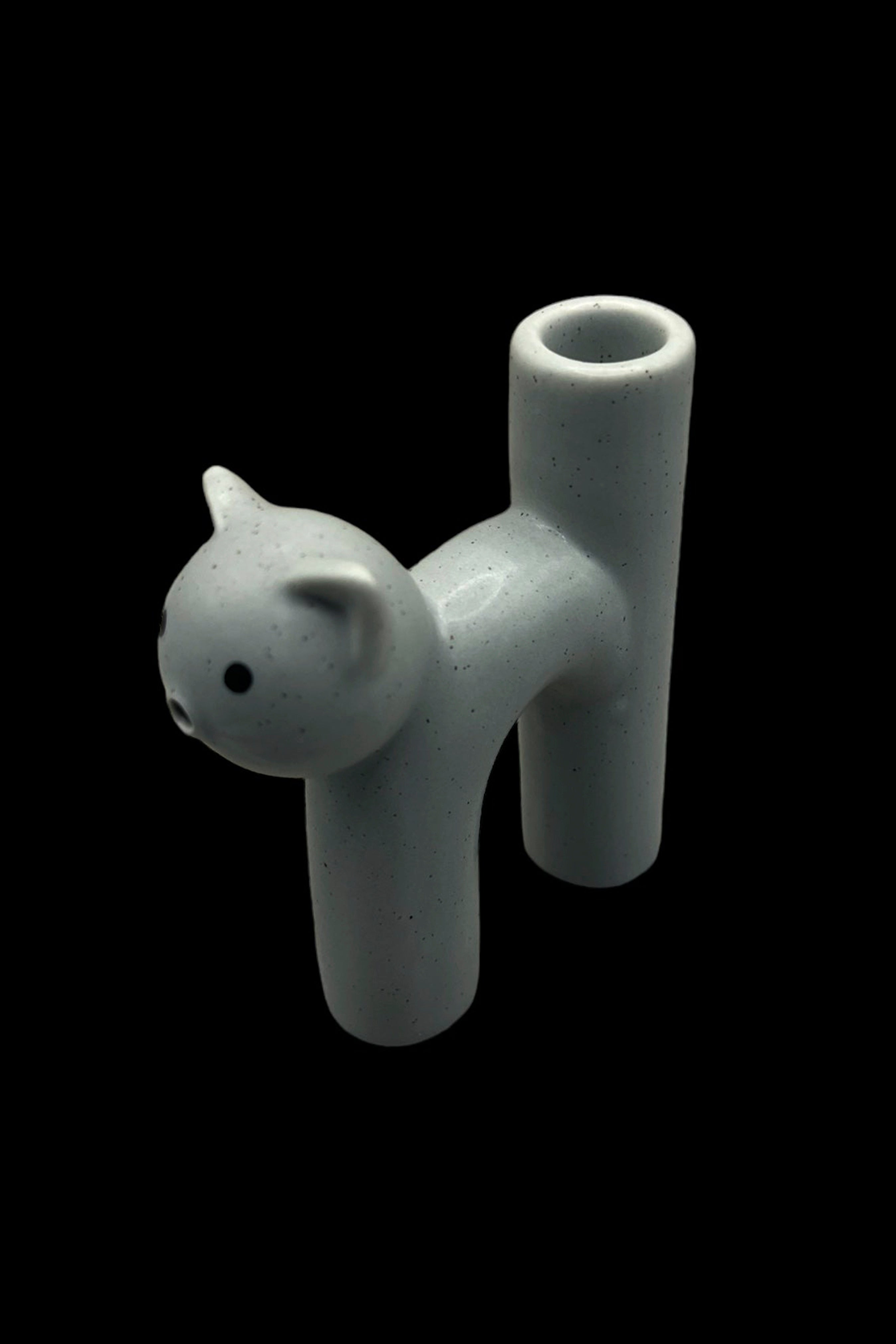 Ceramic cat-shaped cannabis pipe on a black background.