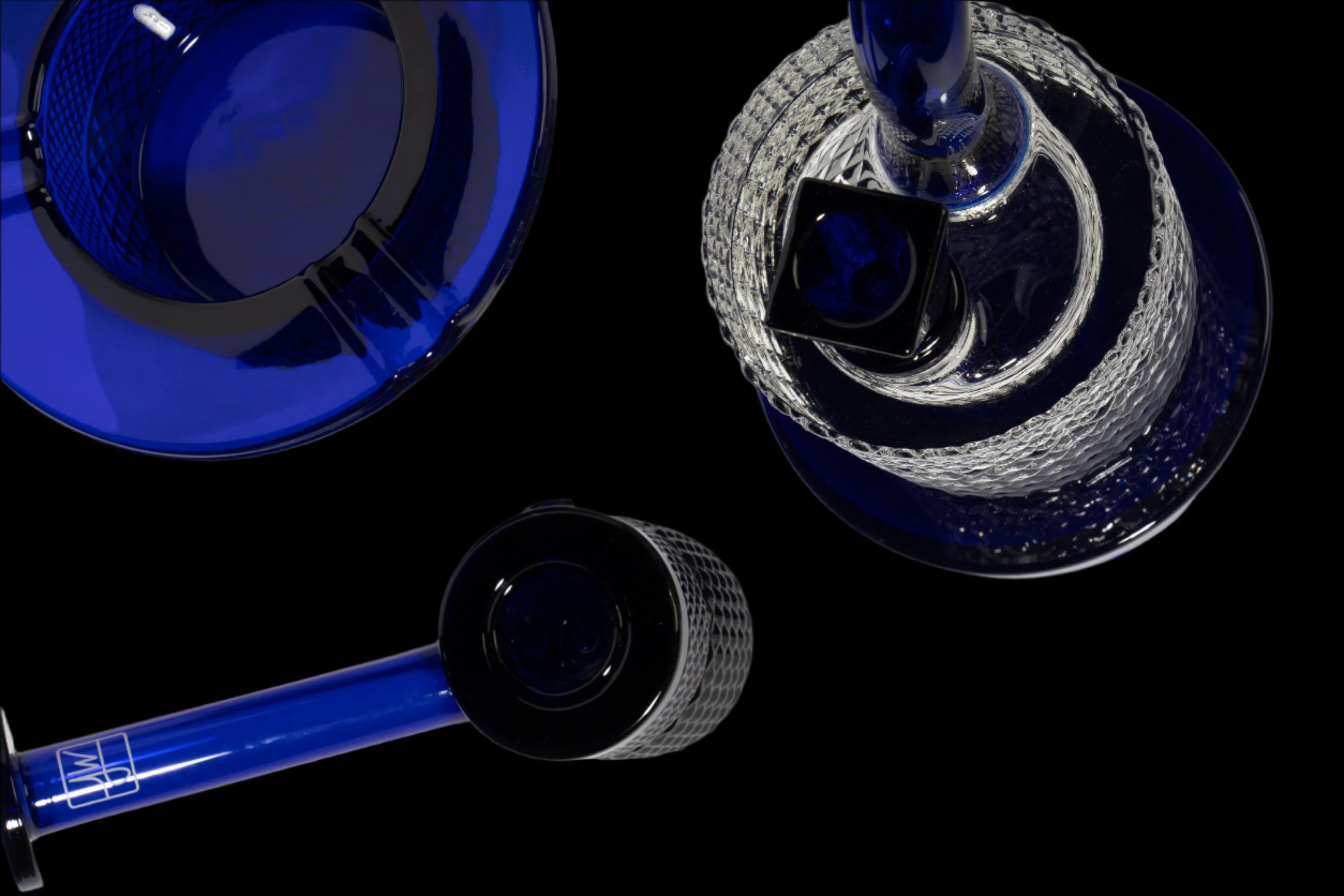 Overhead view of blue glass cannabis water pipe components against a black background.